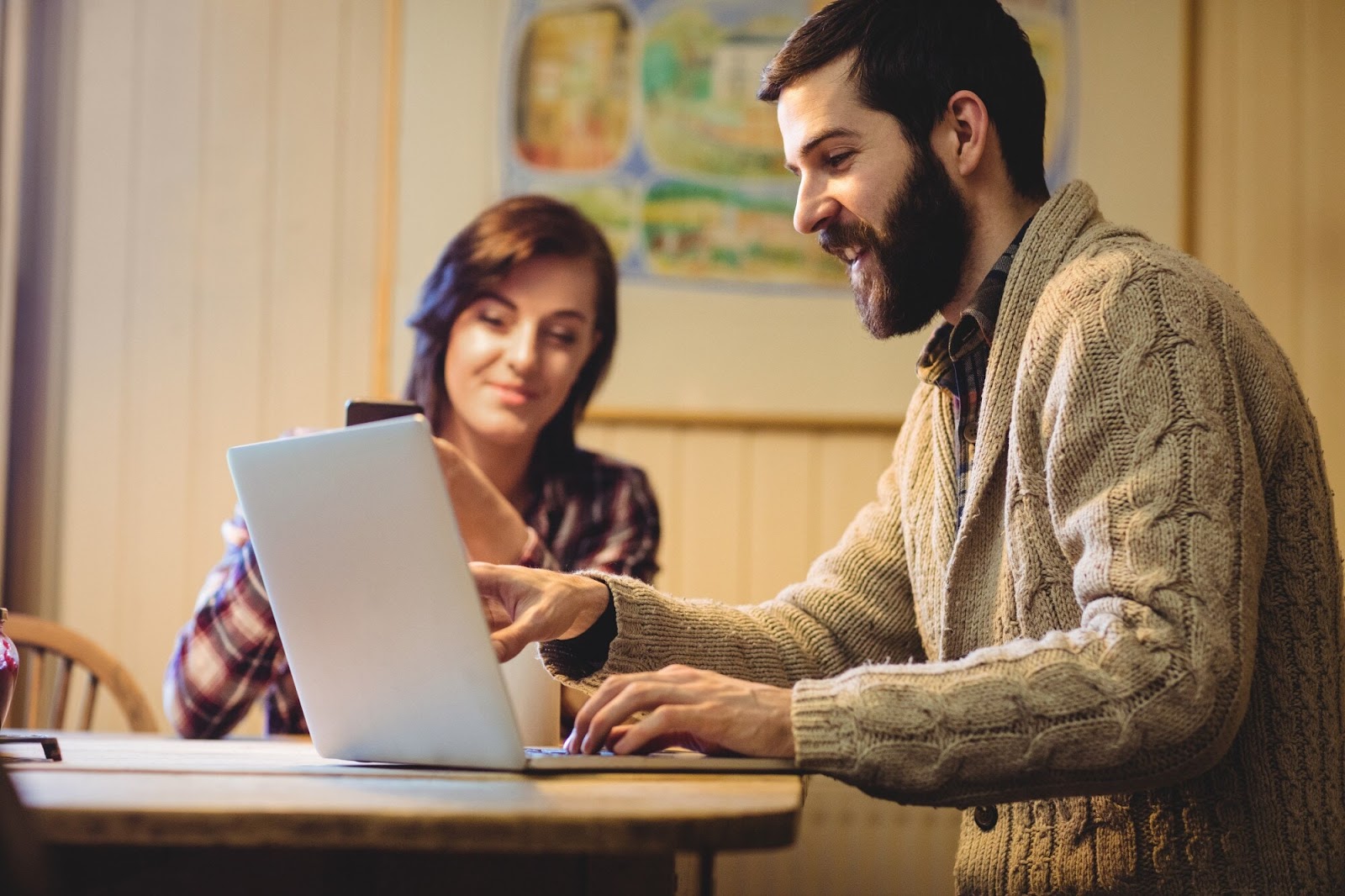 Man using a laptop while a woman looks on