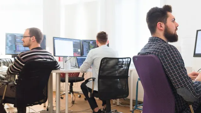 Three colleagues working at desktop computers in a shared office.