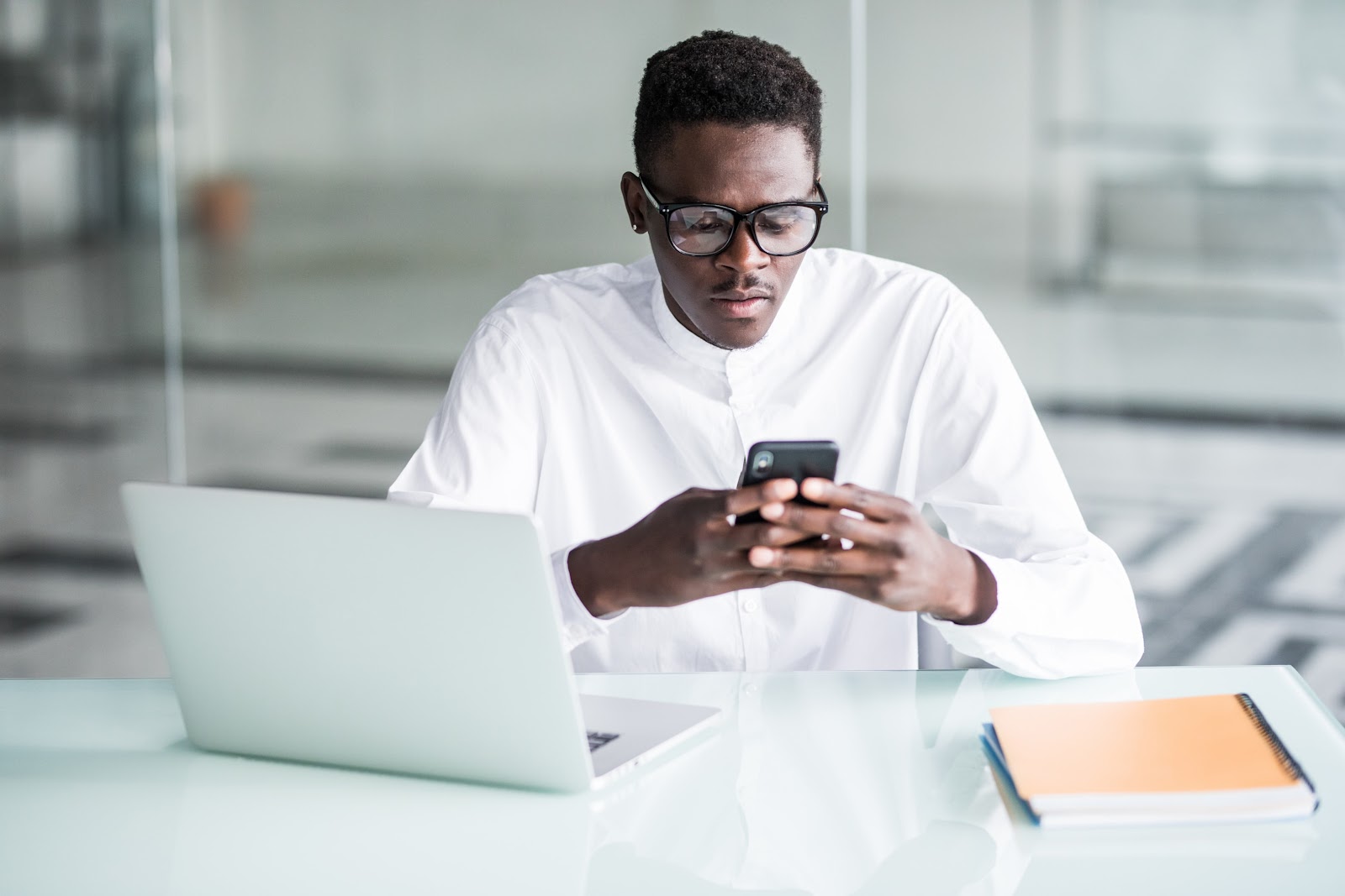 Man using phone and laptop at work